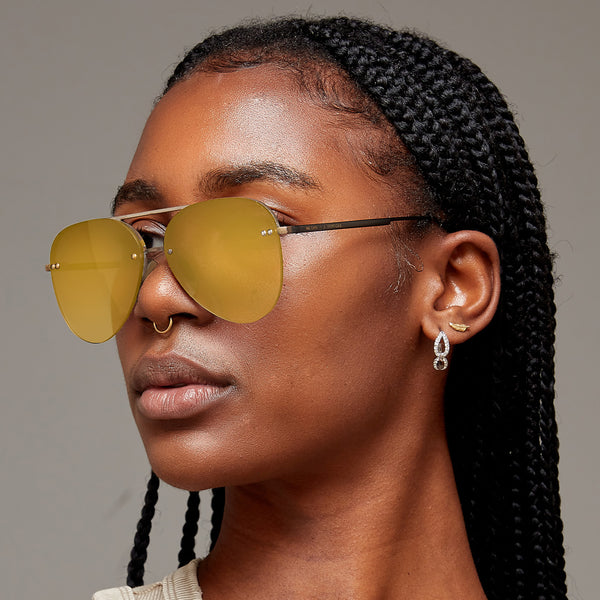 Model of color wearing classic aviators with no nosepad and mirrored gold lenses with metal detailing