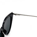 Close up view of white background picture of oversize black glossy cateye sunglasses with metal detailing