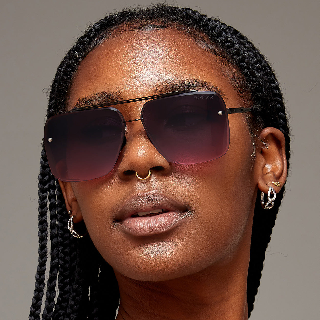 Woman of color wearing faded purple to pink oversize square aviators with no nose pads. 