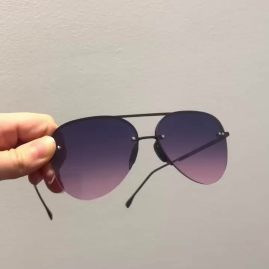 Video of hand-holding classic aviators with no nosepad and faded purple pink lenses with metal detailing, and then putting them on and off the head without ripping out hair.